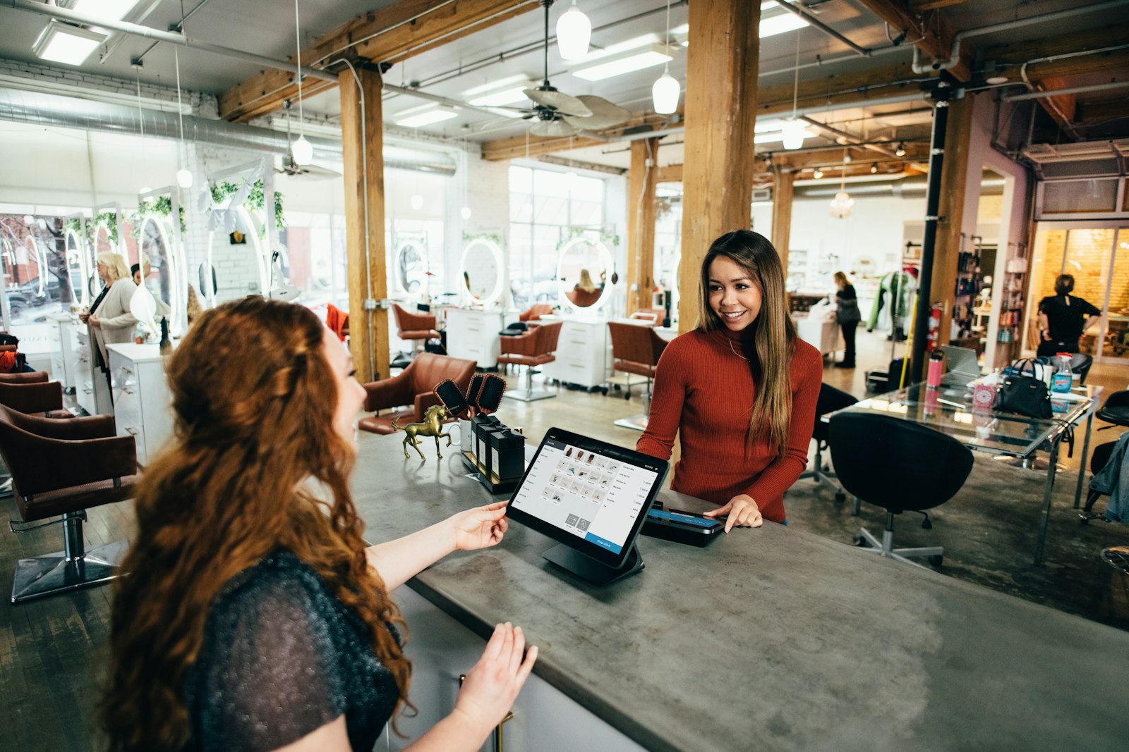 A small business owner showing a customer something on a tablet point-of-sale system